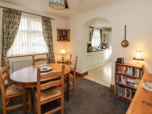 a dining room with a table and chairs and a kitchen at Eusebank in Pooley Bridge