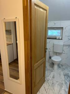 a bathroom with a toilet and a wooden door at Giulia Home in Dezmir