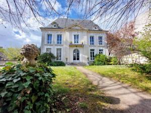 a large white house with a pathway in front of it at La Maucannière in Joué-lès-Tours