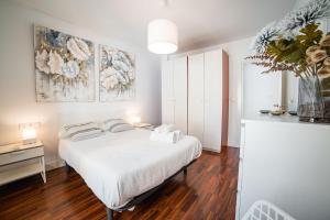 a white bedroom with a white bed and a table at Apartamento La Tana centro in Granada