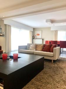 a living room with a couch and a table at Grand appartement avec terrasse in Knokke-Heist