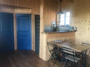 a kitchen with a blue door and a table and chairs at Maison en bois dans un pré in Nuits-sur-Armançon