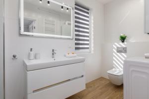 a white bathroom with a sink and a mirror at Apartment with Parking 500 m from The Sea by Renters in Międzywodzie