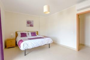 a white bedroom with a bed with purple pillows at Penthouse Papoila in Cabanas de Tavira +12 photos