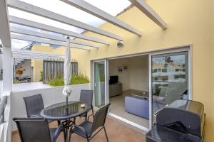a patio with a table and chairs and a living room at Penthouse Papoila in Cabanas de Tavira