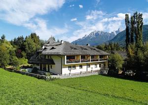 una casa en una colina con montañas en el fondo en Residence Adler en Villabassa
