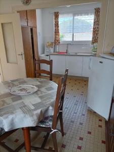 a kitchen with a table and two chairs and a kitchen with a sink at MAISON DE VACANCES in Saint-Vincent-sur-Jard