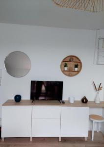 - un salon avec une télévision sur un mur blanc dans l'établissement Escale à Épernay: Studio proche du centre ville, à Épernay
