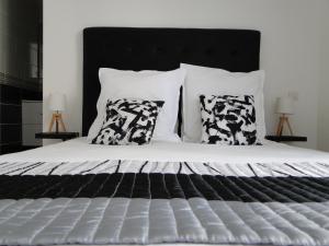 Schlafzimmer mit einem Bett mit schwarzen und weißen Kissen in der Unterkunft L'Amiral in Vichy
