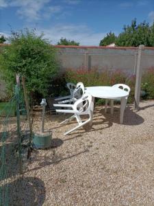 a white table and chair in a garden at MAISON DE VACANCES in Saint-Vincent-sur-Jard