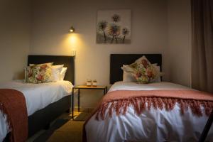 1 dormitorio con 2 camas y mesa auxiliar en VillaZek a modern 2 bedroom open- plan apartment with parking en Pretoria