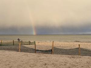 a rainbow over the beach with a beach volleyball net at Längengrad 67 in Fehmarn