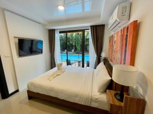 a bedroom with a bed and a tv and a pool at Mai Khao Beach Condotel - family condo in 600 meters to beach in Ban Bo Sai Klang