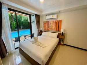 a bedroom with a bed and a large window at Mai Khao Beach Condotel - family condo in 600 meters to beach in Ban Bo Sai Klang