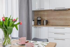 a kitchen with a table with a vase of pink flowers at Apartment with Parking 500 m from The Sea by Renters in Międzywodzie