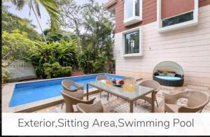 eine Terrasse mit einem Tisch und Stühlen neben einem Pool in der Unterkunft 4BHK Luxury Villa with Private Pool Near Candolim in Marmagao