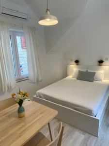 Dormitorio blanco con cama y mesa en Blu Riva Hvar, en Hvar