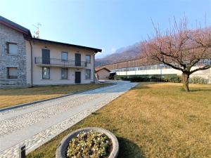 a building with a tree in front of a yard at Winter Spring Summer Apartments in Mergozzo