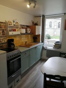 een keuken met blauwe kasten en een groot raam bij Les Fleurs Wimille / Wimereux in Wimille