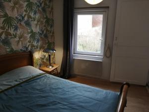 een slaapkamer met een bed en een raam bij Les Fleurs Wimille / Wimereux in Wimille