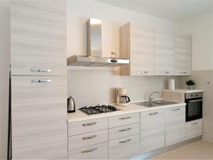 una cucina con armadi bianchi e piano cottura di Winter Spring Summer Apartments a Mergozzo