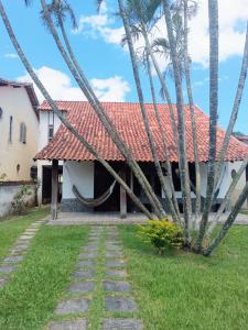una casa con techo rojo y palmeras en Casa sonho sonhado en São Pedro da Aldeia