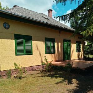 a house with green shutters and a wooden porch at Balatonszemesi Vendégház in Balatonszemes