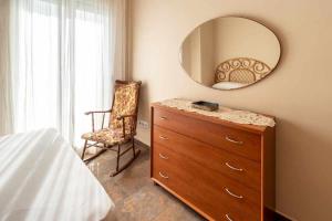 een slaapkamer met een dressoir met een spiegel en een stoel bij Port de Llançà 34 Apartamento con vistas playa in Girona