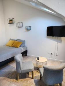- une chambre avec un lit, deux chaises et une télévision dans l'établissement Le Yellow Korner - lit neuf, à Rouen