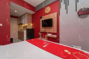 - une chambre avec des murs rouges, un lit et une horloge dans l'établissement RedLiving Apartemen Patra Land Urbano - Kamarku Tower Mid-West, à Bekasi