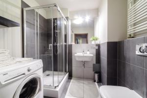 bagno con doccia, lavandino e lavatrice di Apartments of Pawia a Cracovia