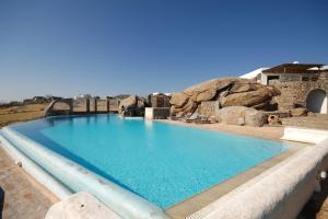 a large blue swimming pool with rocks in the background at Nefeli Sea View Holiday House in Mýkonos City