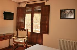 a bedroom with a bed and a window and a chair at Hotel Olimpia in Albarracín