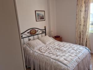 a bedroom with a bed with white sheets and a window at Pareado Mediterrania in Benicarló