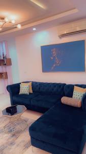 a living room with a blue couch and a painting at Exquisite 2-Bedroom Apt in Oniru in Lagos