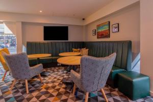 a restaurant with tables and chairs and a flat screen tv at Ramada Encore Leicester City Centre in Leicester