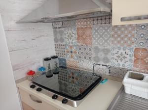 a small kitchen with a stove and tiles on the wall at La ramasola & il datterino in Pezze di Greco +100 photos