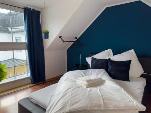 um quarto com uma cama branca e uma parede azul em Design Wohnung nähe Uni em Koblenz