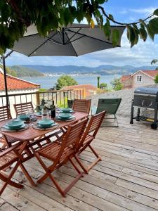 una mesa de madera y sillas en una terraza con sombrilla en La casita de Ouriceira, en Combarro