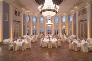 a ballroom with white tables and chairs and a chandelier at ATLANTIC Grand Hotel Travemünde in Travemünde