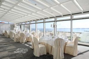 a banquet hall with white tables and chairs and windows at ATLANTIC Grand Hotel Travemünde in Travemünde