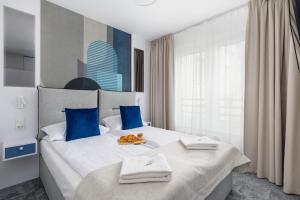 1 dormitorio con 1 cama blanca grande con almohadas azules en Apartments Nad Parsętą Młyńska by Renters en Kołobrzeg