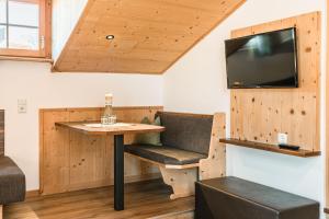 Zimmer mit einem Tisch und einem TV an der Wand in der Unterkunft Ansitz Zehentner in Lajen