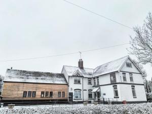 uma grande casa branca com neve no telhado em The Swan Inn Letton em Letton