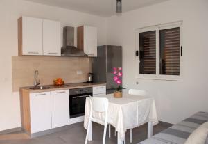 a kitchen with white cabinets and a table with chairs at Apartment Orebic 4526b in Orebić