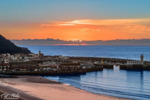 a beach with a city and the ocean at sunset at Seadream Luxury Holiday Home with Hot Tub Sleeps 6 in Scarborough