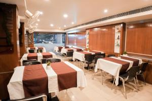 um restaurante com mesas e cadeiras num quarto em Pleasure Inn em Bhopal