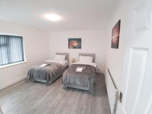 a room with two beds and a window at Exquisite Two Bed Apartment in Grays - Free Wi-Fi and Netflix in Stifford