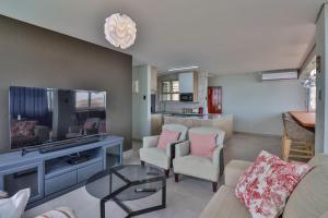 a living room with a couch and chairs and a tv at Shangri-La Self Catering Holiday Apartment in Kingsburgh