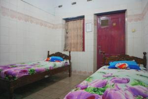 OYO Life 1972 Aman Family Inn Syariah في Ponorogo: غرفة بسريرين وباب احمر
